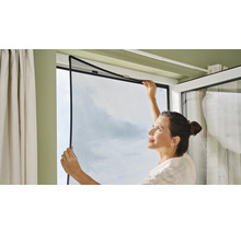 Frau montiert Insektenschutzgitter am Fenster