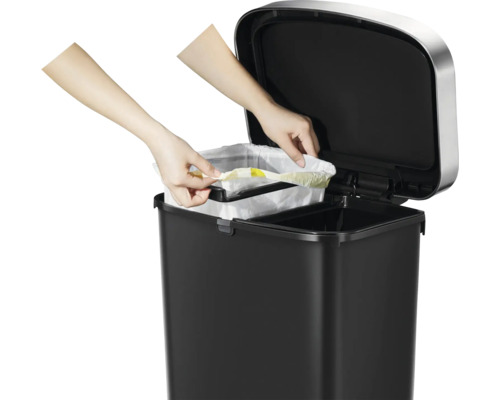 Abfalleimer mit zwei Fächern und Händen, die einen Müllbeutel einsetzen