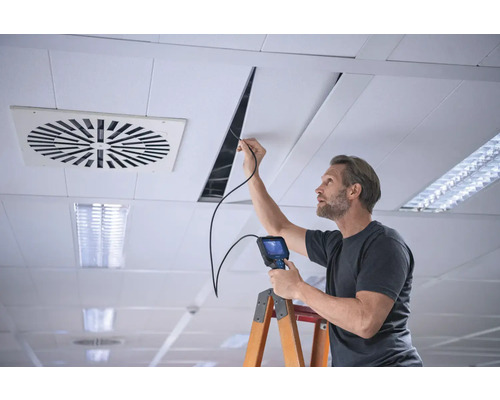 Mann mit Endoskop bei der Deckeninspektion auf einer Leiter