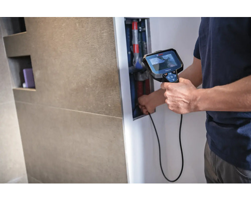 Ein Mann benutzt ein Inspektionskamera-Werkzeug zur Rohrleitungsinspektion im Badezimmer.