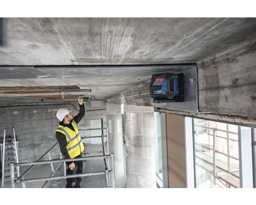 Ein Bauarbeiter benutzt einen Linienlaser zur Ausrichtung an einer Baustelle.