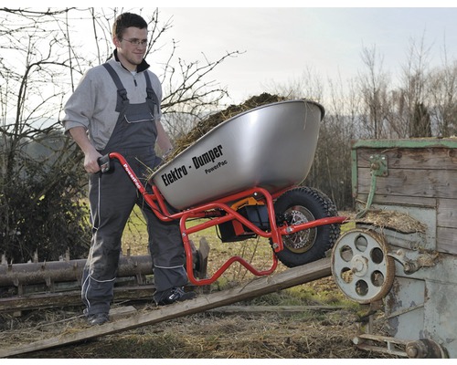 Mann schiebt eine beladene Elektromotor-Schubkarre mit Kippfunktion über eine Rampe