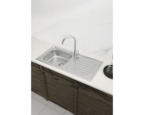 Spüle aus Edelstahl mit Abtropffläche und Wasserhahn auf einer Küchentheke montiert