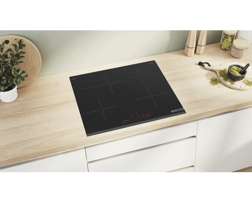 Schwarzes Glaskeramikkochfeld mit vier Kochzonen auf einer hellen Arbeitsfläche