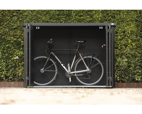 Fahrrad in einer Fahrradgarage vor einer grünen Hecke