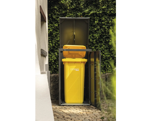Mülltonnenbox mit gelber Mülltonne und geöffneter Tür vor einer grünen Pflanzenwand