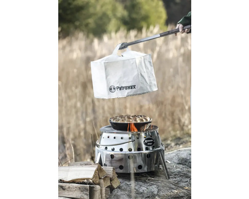 Petromax Atago Grill mit Abdeckhaube, Zange und zubereitetem Gericht im Freien