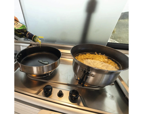 Zwei Töpfe auf einem Herd, in einem Topf kocht Pasta, in den anderen wird Öl gegossen.