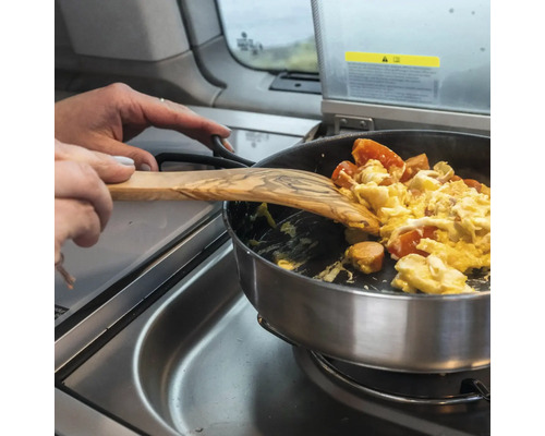 Eier mit Tomaten und Wurst werden mit einem Olivenholzspatel in einer Pfanne auf einem Herd zubereitet.