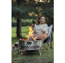 Feuerstelle aus Edelstahl mit Frau, die ein Glas Wein trinkt und in einem Stuhl sitzt