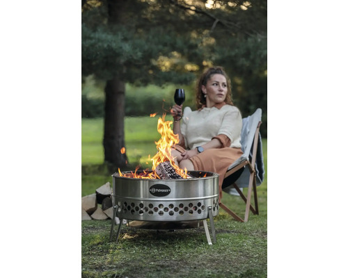 Feuerstelle aus Edelstahl mit Frau, die ein Glas Wein trinkt und in einem Stuhl sitzt