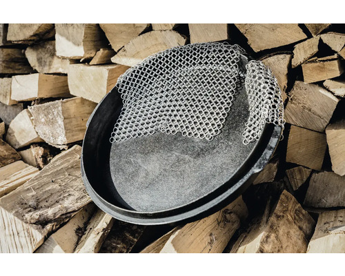 Gusseisenpfanne mit Kettenreiniger auf Holzstapel