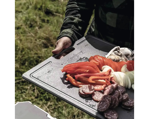 Person hält Schneidebrett mit Wurst, Paprika, Zwiebeln und Champignons