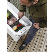 Person öffnet eine weiße Kühlbox mit Gemüse und Fleisch auf einer Holzterrasse