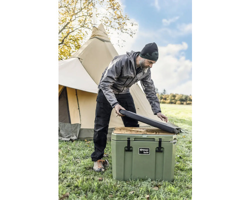 Mann öffnet Kühlbox im Freien vor einem Zelt