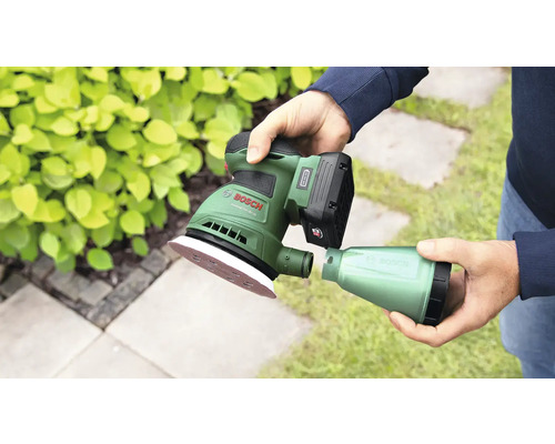 Akkuschleifer mit Staubbehälter in der Hand