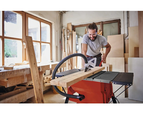 Mann schneidet Holz mit einer Tischkreissäge in einer Werkstatt