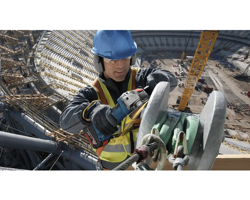 Ein Bauarbeiter schleift Metall mit einem Winkelschleifer auf einer Baustelle.