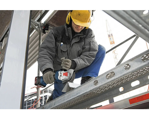 Handwerker beim Schneiden eines Werkstücks mit einem Akku-Winkelschleifer auf einem Gerüst.