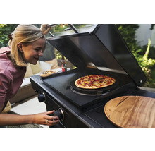 Frau bereitet Pizza auf einem schwarzen Gasgrill zu.