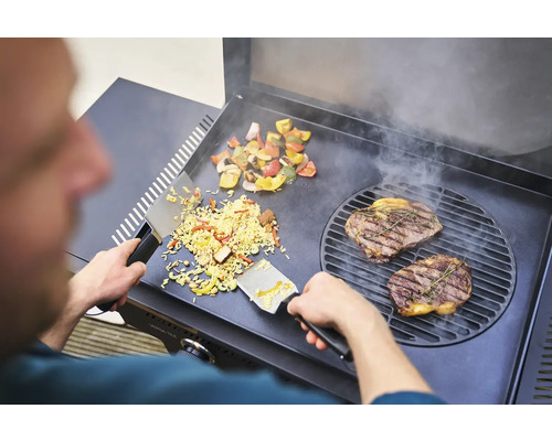 Mann bereitet Steak, Gemüse und Reis auf einem Grill zu