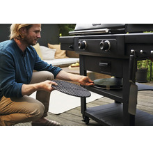 Mann bereitet Holzkohlegrill mit Grillrost und Pizzastein vor