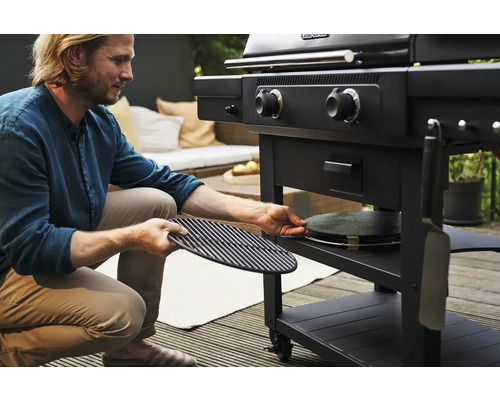 Mann bereitet Holzkohlegrill mit Grillrost und Pizzastein vor