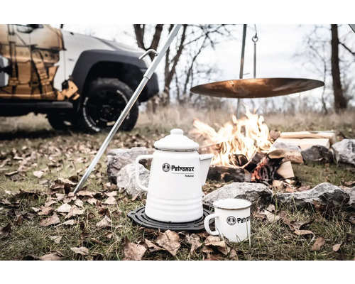 Szene mit weißem Petromax Perkomax Kaffeebereiter, Tasse, Lagerfeuer und Auto im Hintergrund