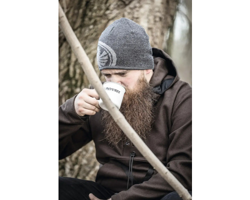Mann mit Bart, Mütze und Petromax Emaille Tasse trinkt im Freien.