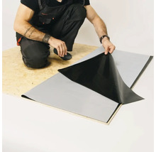 Handwerker bringt eine Abdichtungsbahn auf einer Holzplatte an