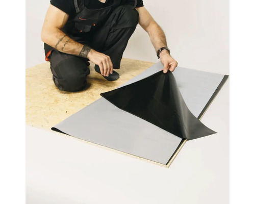 Handwerker bringt eine Abdichtungsbahn auf einer Holzplatte an