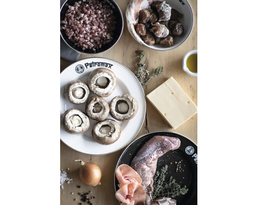 Zutaten für Pilzpfanne mit Speckwürfeln, Datteln, Käse, Wildfleisch, Zwiebeln und Kräutern auf Holztisch