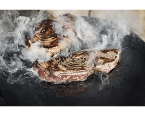 Zwei Steaks mit Rauchentwicklung auf einer Grillplatte