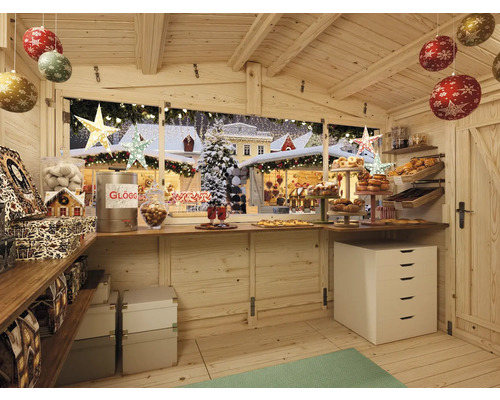 Innenansicht eines Holzhauses mit weihnachtlicher Dekoration, Gebäckauslage und Blick auf einen Weihnachtsmarkt.