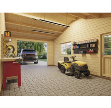 Innenansicht einer Garage mit Rasentraktor, Werkbank und Regalen.