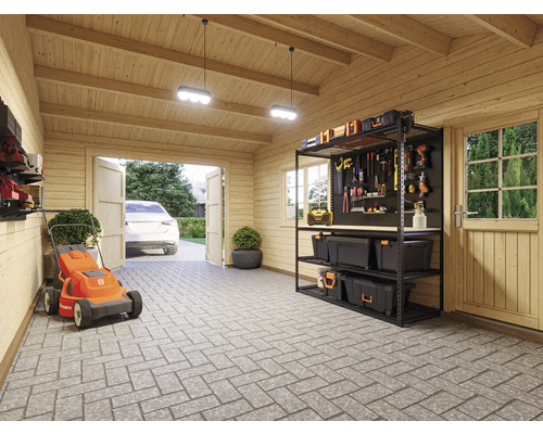 Eine Garage mit einem Rasenmäher, einem Regal und Werkzeugen.