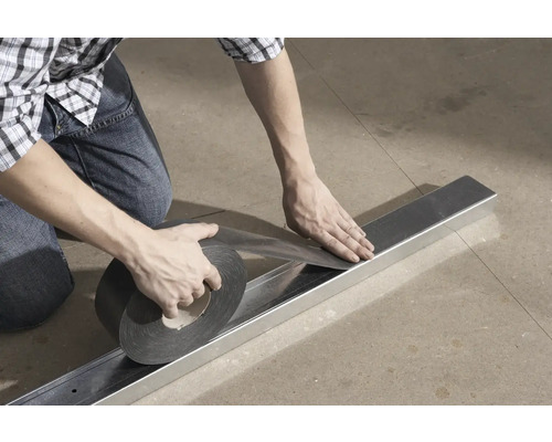 Mann befestigt Dichtungsband auf einem Metallprofil