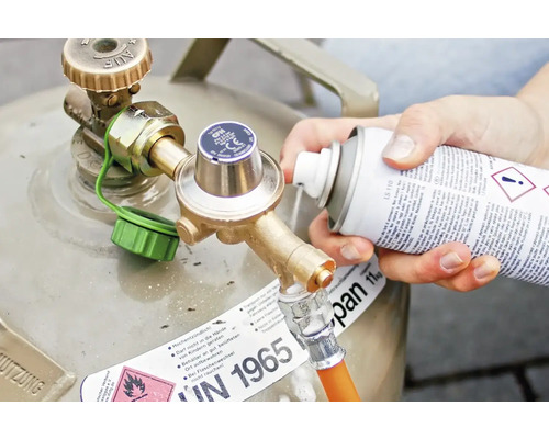 Person sprüht Reiniger auf Gasflaschen-Anschluss