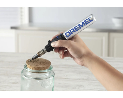 Eine Hand verwendet einen Dremel VersaFlame zum Gravieren eines Korkdeckels auf einem Einmachglas.