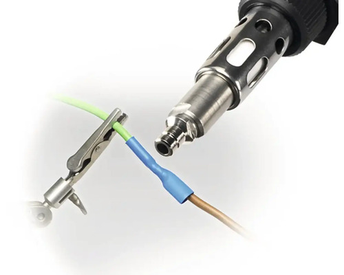 Heißluftpistole verbindet zwei Kabel mit Schrumpfschlauch, fixiert mit Krokodilklemme