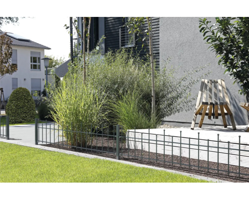 Gartenszene mit Metallzaun zur Abgrenzung eines Grundstücks mit Rasenflächen und Bepflanzung