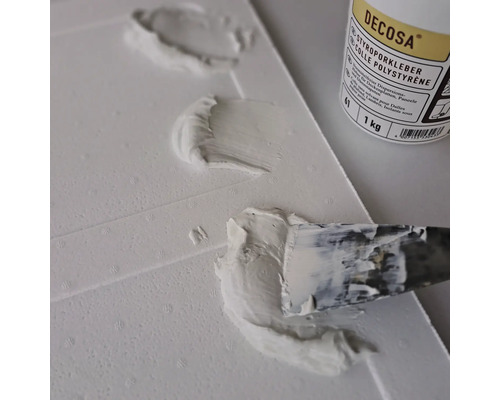 Auftragen von Decosa Styroporkleber auf eine Styroporplatte mit einem Spachtel