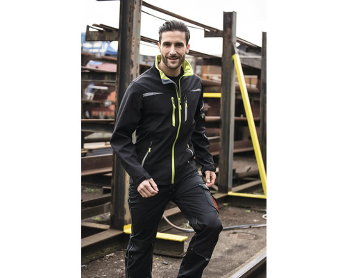 Mann trägt eine schwarze Softshelljacke und Arbeitshose