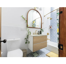 Badezimmer mit Toilette, Waschtischunterschrank, Spiegel und Badewanne unter einer Dusche mit Duschvorhang