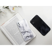 Zwei Handyhüllen mit Marmormuster liegen auf einem aufgeschlagenen Buch.