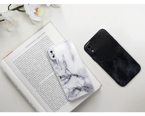 Zwei Handyhüllen mit Marmormuster liegen auf einem aufgeschlagenen Buch.