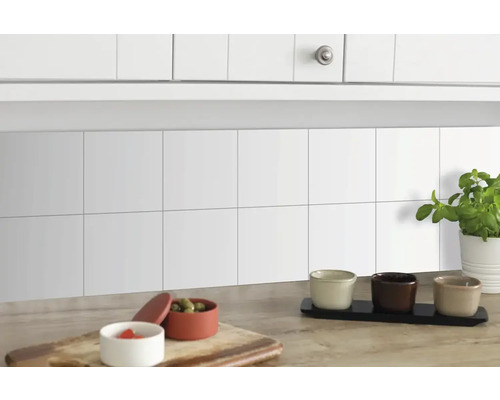 Selbstklebende Wandfliesen Wall Tiles Uni weiß 15,25 x 15,25 cm 6 St. Küchenszene mit weißen Fliesen, Schränken und dekorativen Elementen auf einer Arbeitsplatte
