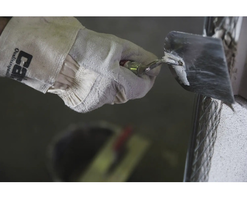 Hand mit Arbeitshandschuh und Maurerkelle beim Verputzen