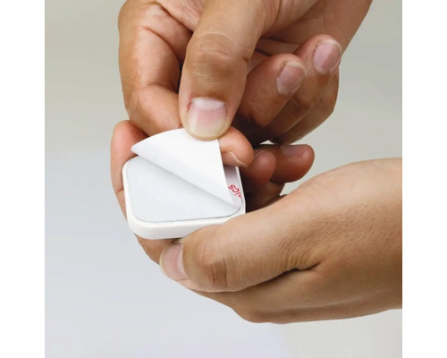 Hände entfernen die Schutzfolie von einem Klebepad