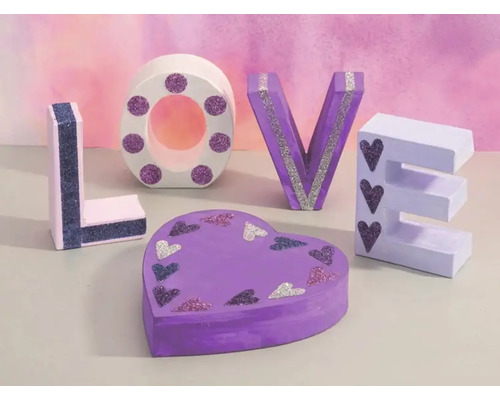 Dekorative Buchstaben und eine herzförmige Schachtel bilden das Wort Liebe.